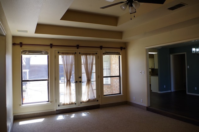 unfurnished room featuring a ceiling fan, carpet, visible vents, baseboards, and a raised ceiling