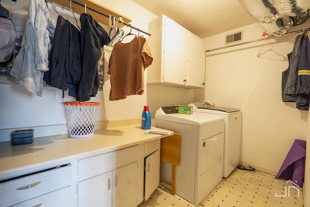 clothes washing area featuring cabinets, a textured ceiling, and independent washer and dryer