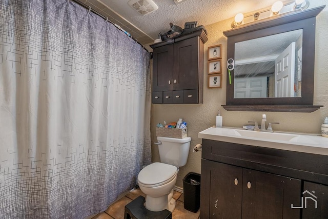 bathroom featuring tile patterned flooring, vanity, toilet, and a textured ceiling