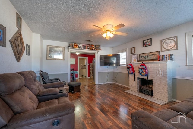 living room featuring ceiling fan, hardwood / wood-style floors, a textured ceiling, and a fireplace