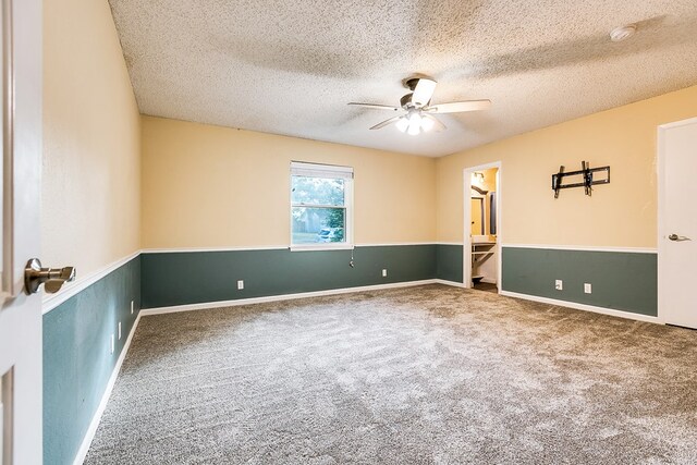 empty room with ceiling fan, carpet floors, and a textured ceiling