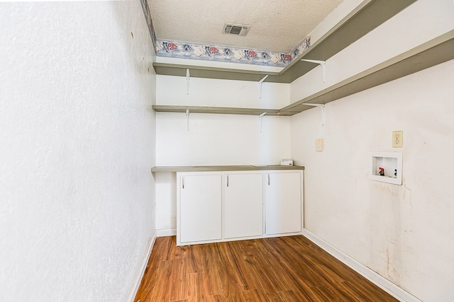 laundry area featuring cabinets, dark wood-type flooring, washer hookup, and a textured ceiling