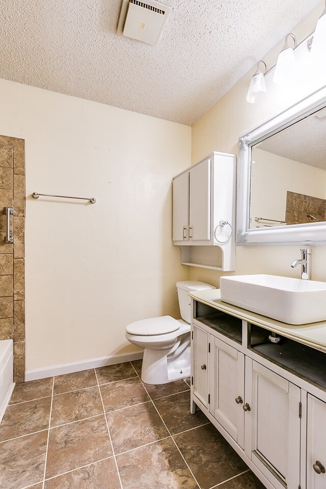 bathroom featuring vanity, a textured ceiling, and toilet