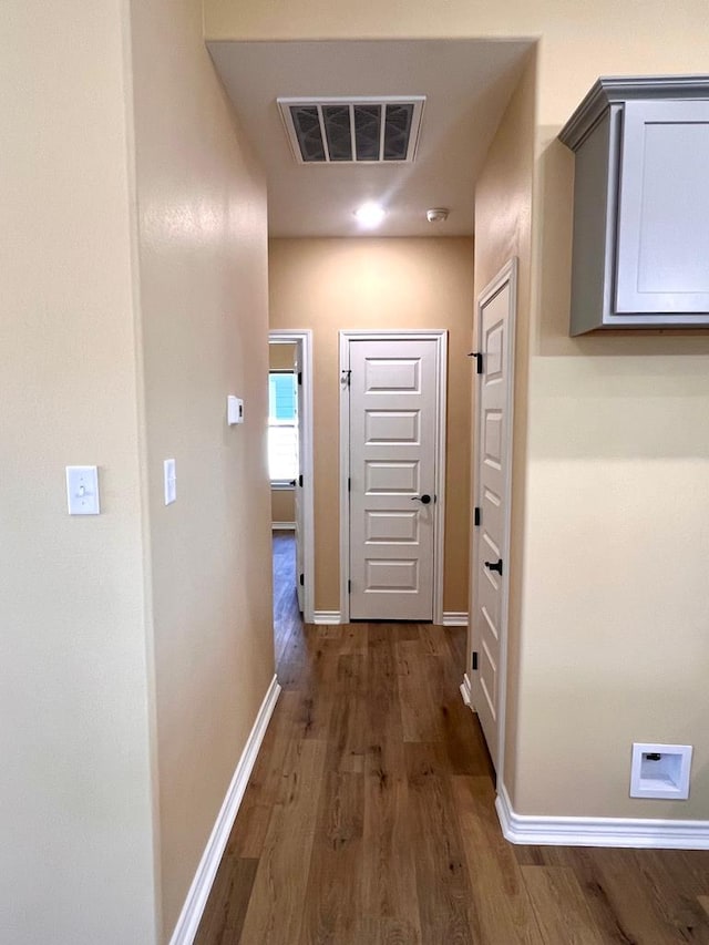 hallway with visible vents, baseboards, and dark wood-style floors