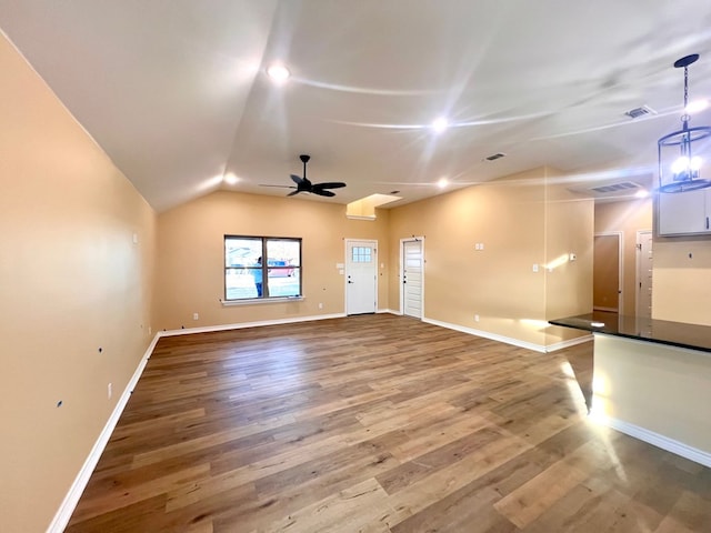 unfurnished living room featuring a ceiling fan, vaulted ceiling, wood finished floors, and baseboards