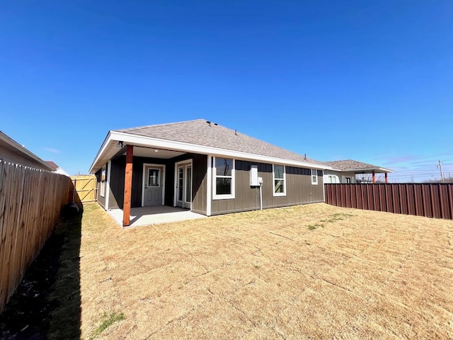 back of property with a patio, a shingled roof, and a fenced backyard