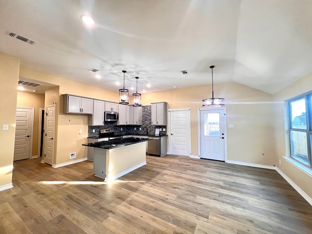 kitchen with backsplash, visible vents, appliances with stainless steel finishes, and a center island