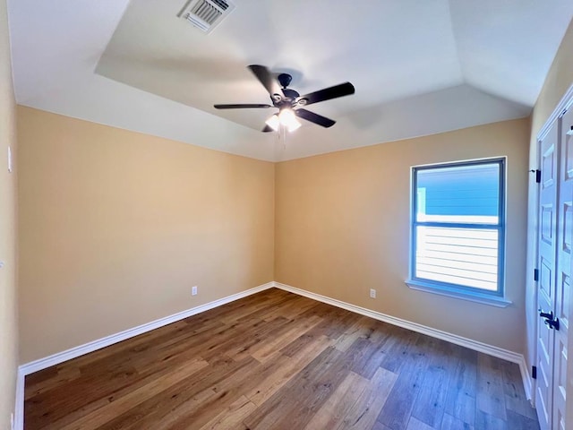 empty room featuring visible vents, dark wood-type flooring, baseboards, and vaulted ceiling