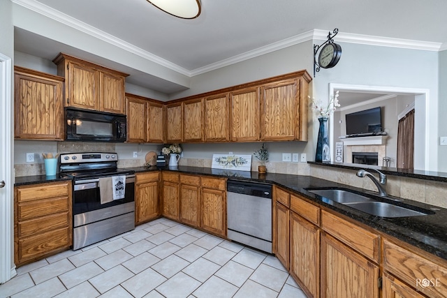 kitchen featuring sink, crown molding, light tile patterned floors, appliances with stainless steel finishes, and a fireplace