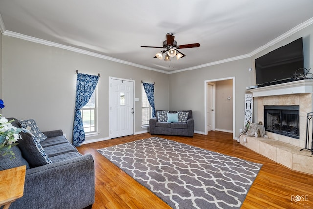 living room featuring hardwood / wood-style floors, a fireplace, ornamental molding, and ceiling fan