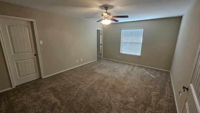 empty room featuring ceiling fan and dark colored carpet