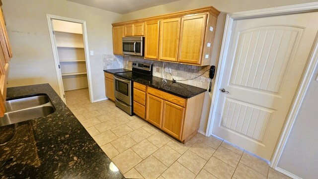 kitchen featuring tasteful backsplash, appliances with stainless steel finishes, sink, and dark stone counters