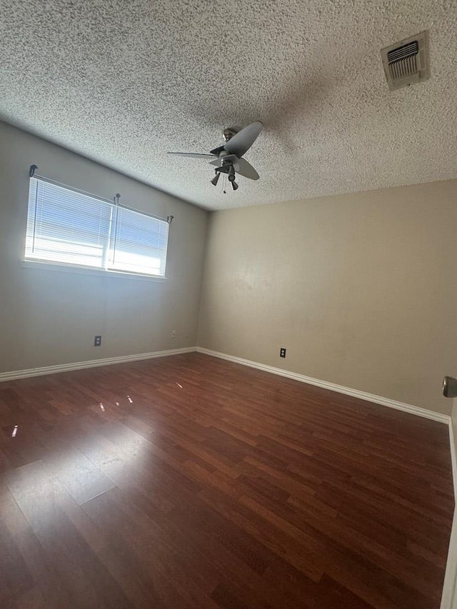 empty room with dark hardwood / wood-style flooring, a textured ceiling, and ceiling fan