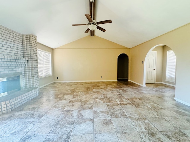 unfurnished living room featuring a brick fireplace, vaulted ceiling with beams, and ceiling fan