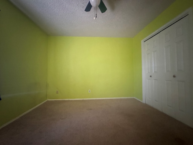 unfurnished bedroom with ceiling fan, carpet floors, a closet, and a textured ceiling