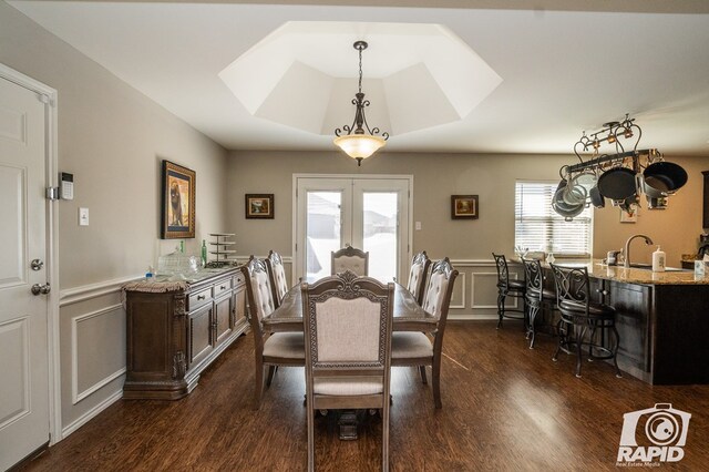 dining space featuring dark wood-style floors, french doors, and a decorative wall