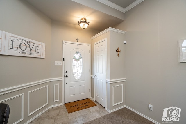 entrance foyer featuring crown molding, a wainscoted wall, and a decorative wall