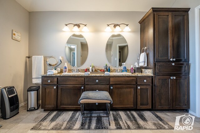 full bath featuring baseboards, double vanity, and heating unit