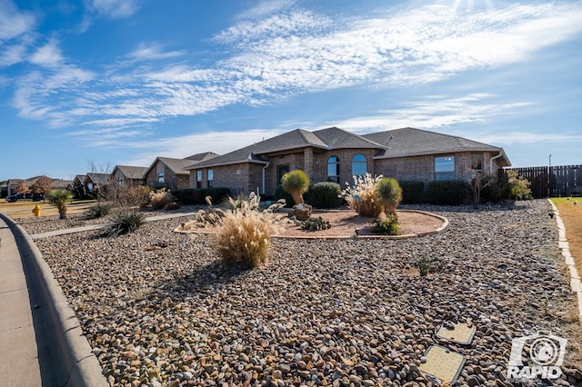 view of front of house featuring brick siding, fence, and a residential view