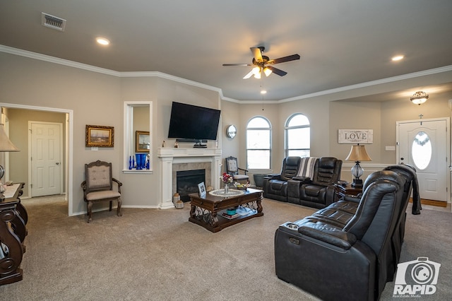 carpeted living room featuring crown molding, a tile fireplace, and ceiling fan