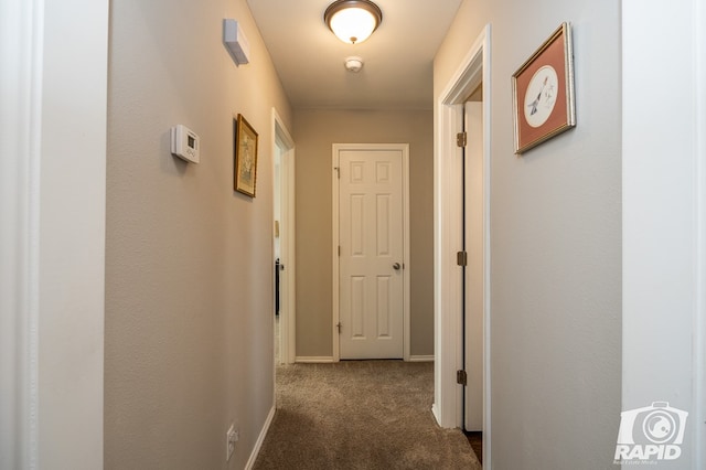 hallway featuring carpet flooring and baseboards