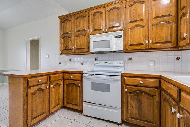 kitchen with white appliances, light tile patterned floors, a peninsula, light countertops, and brown cabinets