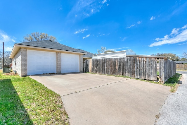 view of side of property featuring a garage, brick siding, and fence