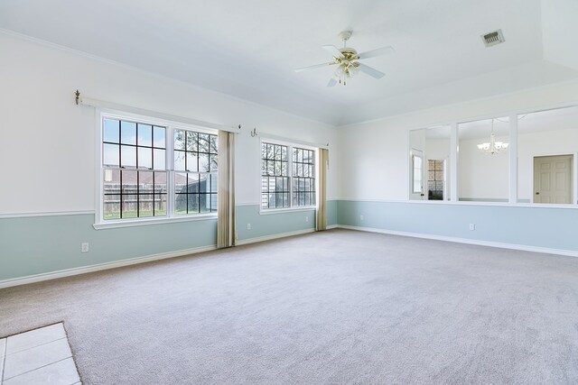 carpeted empty room featuring ornamental molding, ceiling fan with notable chandelier, visible vents, and baseboards