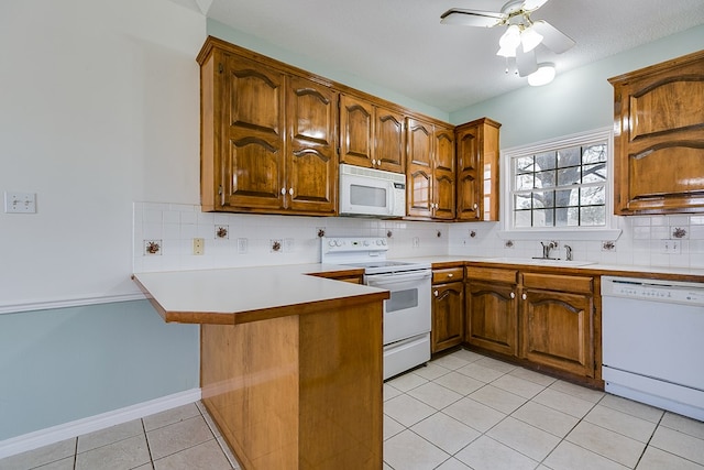 kitchen with a sink, white appliances, a peninsula, light tile patterned floors, and decorative backsplash