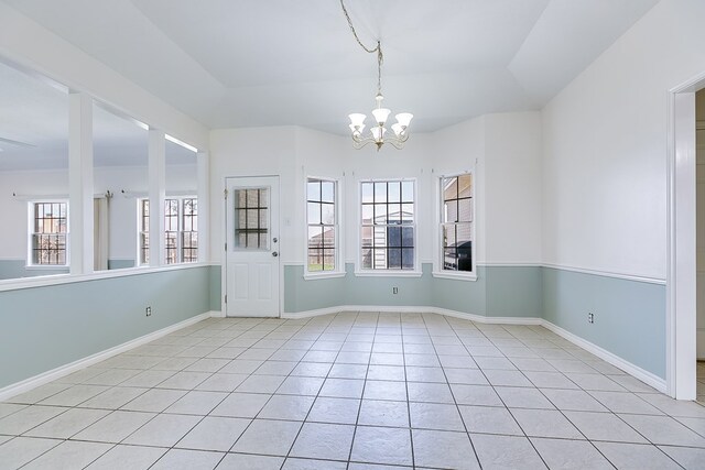 unfurnished room with light tile patterned floors, baseboards, and an inviting chandelier