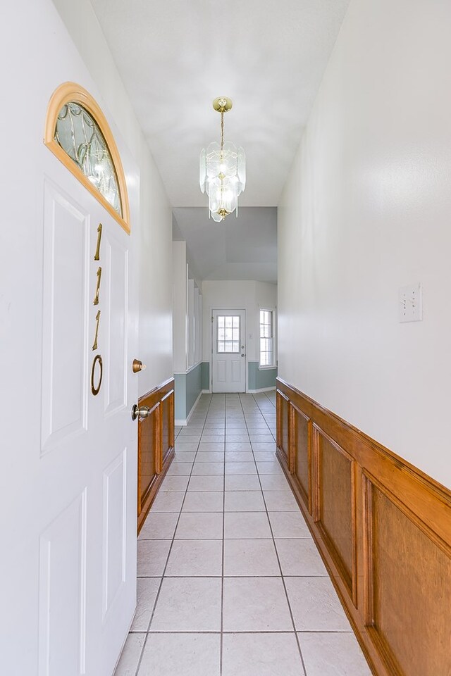 foyer featuring a notable chandelier, light tile patterned floors, and baseboards