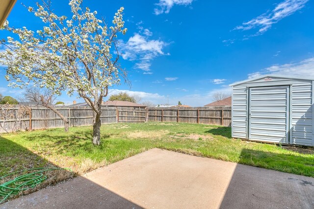 view of yard featuring an outbuilding, a fenced backyard, a shed, and a patio area