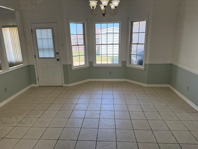 interior space featuring light tile patterned flooring, a notable chandelier, and baseboards