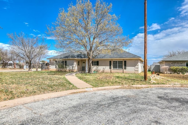 single story home with a front lawn, fence, and brick siding