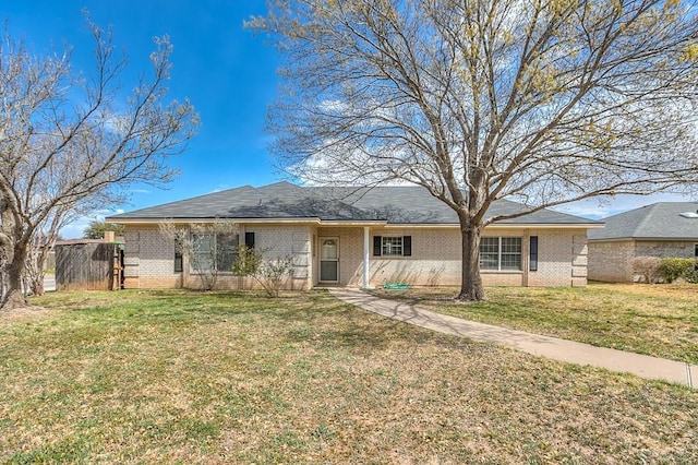 ranch-style home featuring brick siding, a front yard, and fence