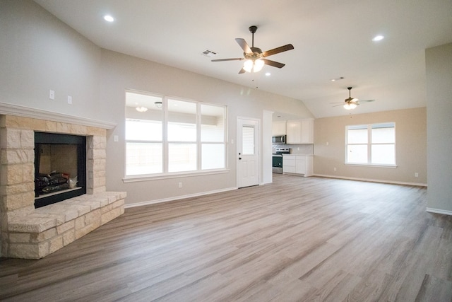 unfurnished living room featuring lofted ceiling, a fireplace, ceiling fan, and light wood-type flooring