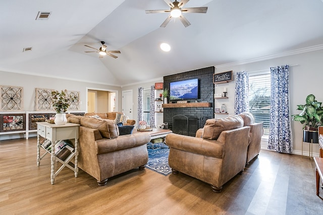 living room with a ceiling fan, a brick fireplace, visible vents, and wood finished floors