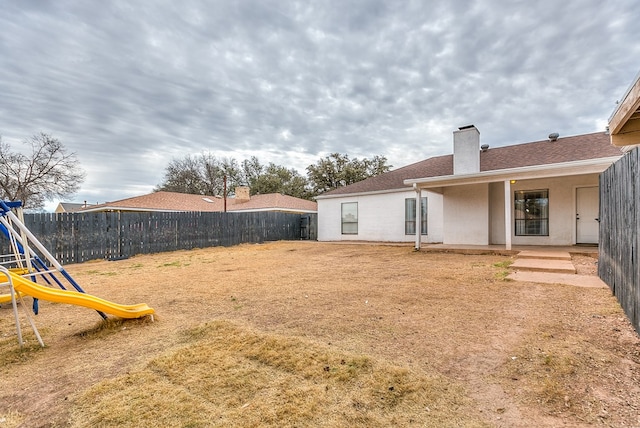 view of yard featuring a fenced backyard, a playground, and a patio