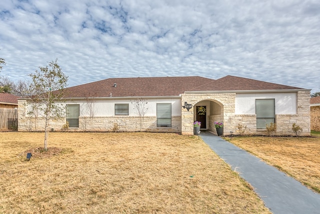 ranch-style home featuring stone siding, roof with shingles, a front lawn, and stucco siding