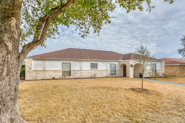 view of front of house featuring stone siding, a front yard, and stucco siding