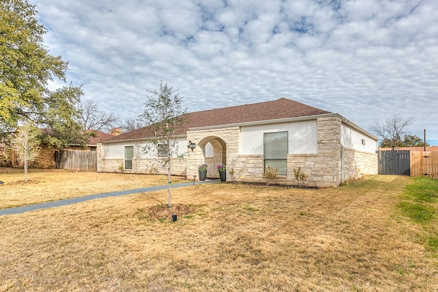 ranch-style house with stone siding, fence, a front lawn, and stucco siding