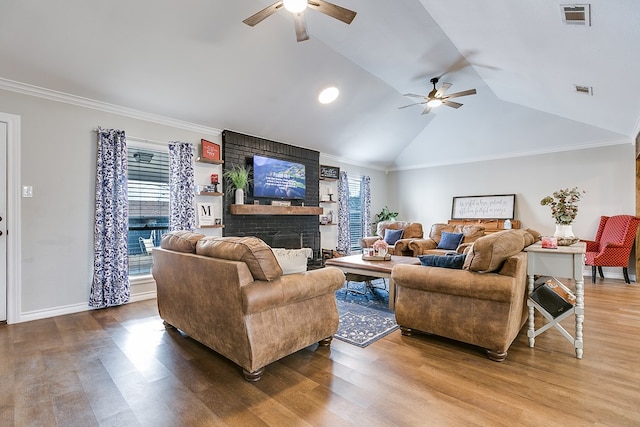 living area with crown molding, visible vents, a brick fireplace, vaulted ceiling, and wood finished floors