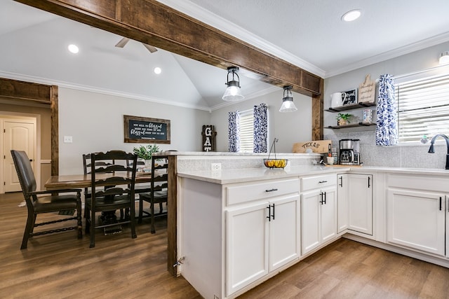 kitchen featuring white cabinets, dark wood-style floors, vaulted ceiling with beams, a peninsula, and crown molding