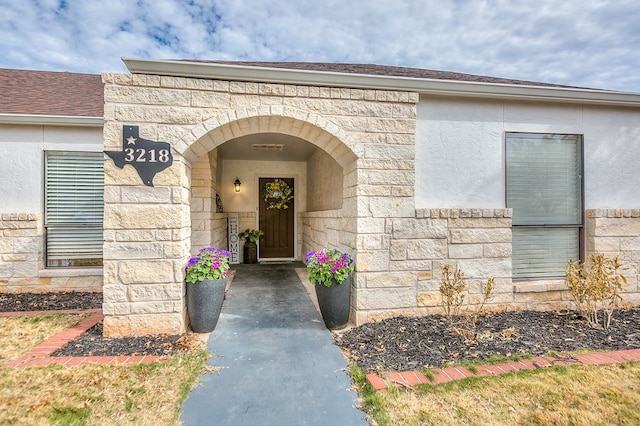 entrance to property featuring stone siding and stucco siding