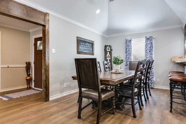 dining room with lofted ceiling, crown molding, baseboards, and wood finished floors