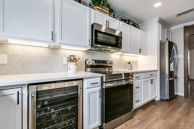 kitchen featuring appliances with stainless steel finishes, light countertops, beverage cooler, and visible vents