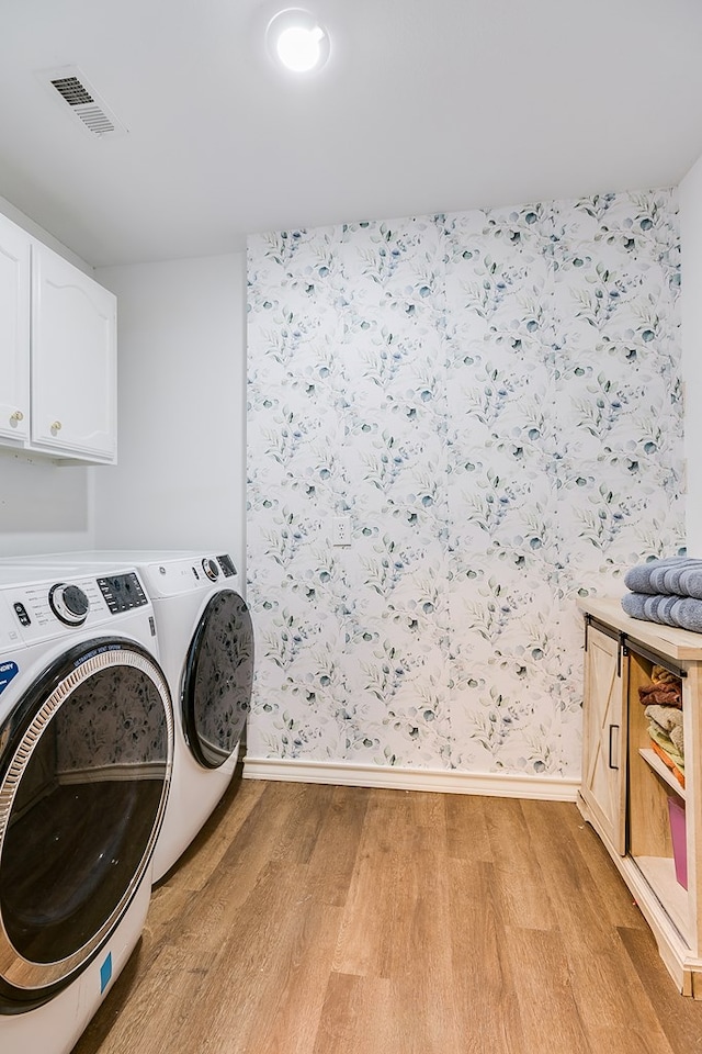 laundry area with light wood-type flooring, cabinet space, washing machine and dryer, and visible vents