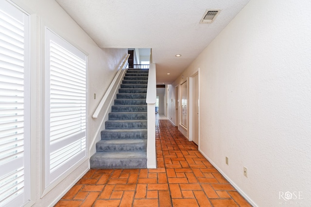 stairway featuring a textured ceiling and a wealth of natural light