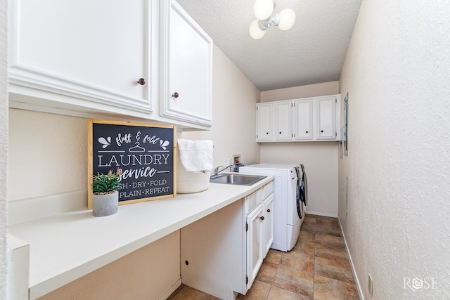 clothes washing area with sink, washing machine and dryer, cabinets, and a textured ceiling