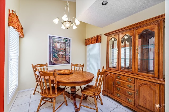 dining area with a chandelier, light tile patterned floors, and a textured ceiling